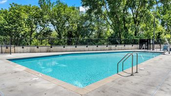 A large outdoor swimming pool surrounded by a fence and trees.