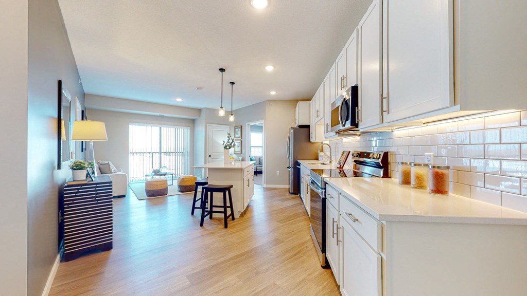 a kitchen and living room with white cabinets and wood floors