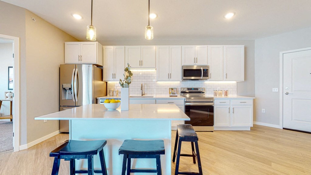 a kitchen with white cabinets and a blue island with three blue stools