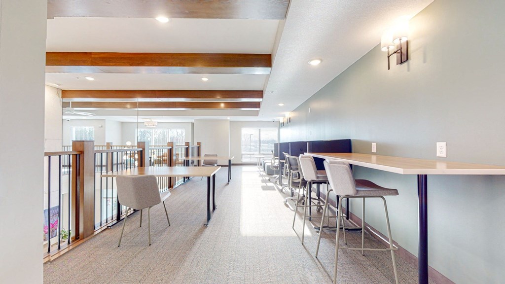 a room with a row of tables and chairs on the left and a hallway on the right