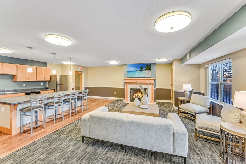 a living room with couches and chairs and a kitchen with a fireplace