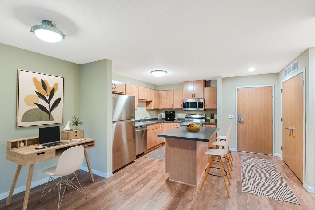 an open kitchen and dining room with wood flooring and stainless steel appliances