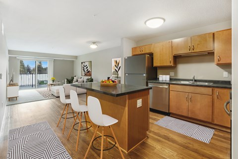 A kitchen with a black counter top and white chairs.