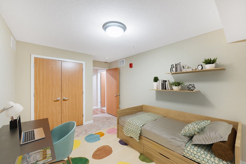 a bedroom with a bed and a desk with a laptop