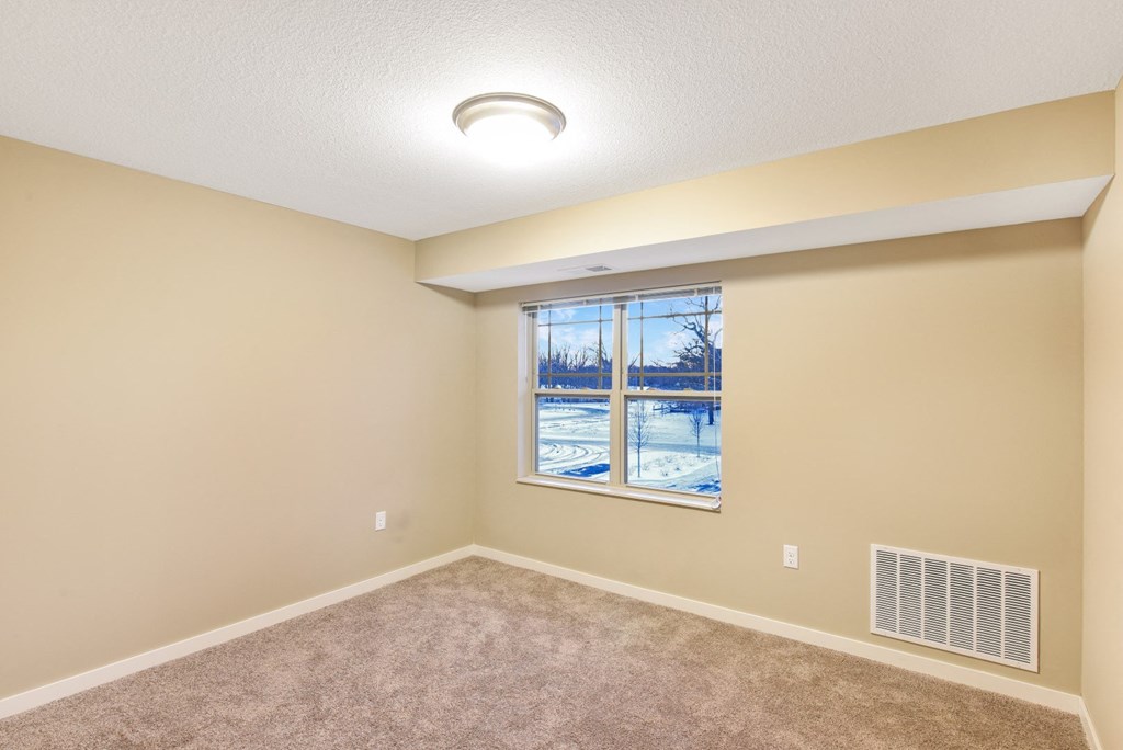 an empty living room with a window and carpet
