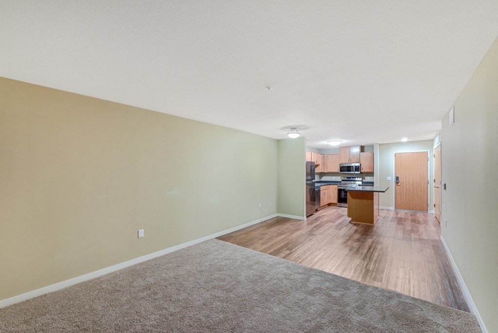 the living room and kitchen of an apartment with wood flooring