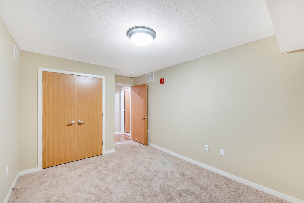 a spacious living room with carpet and a door to a bedroom