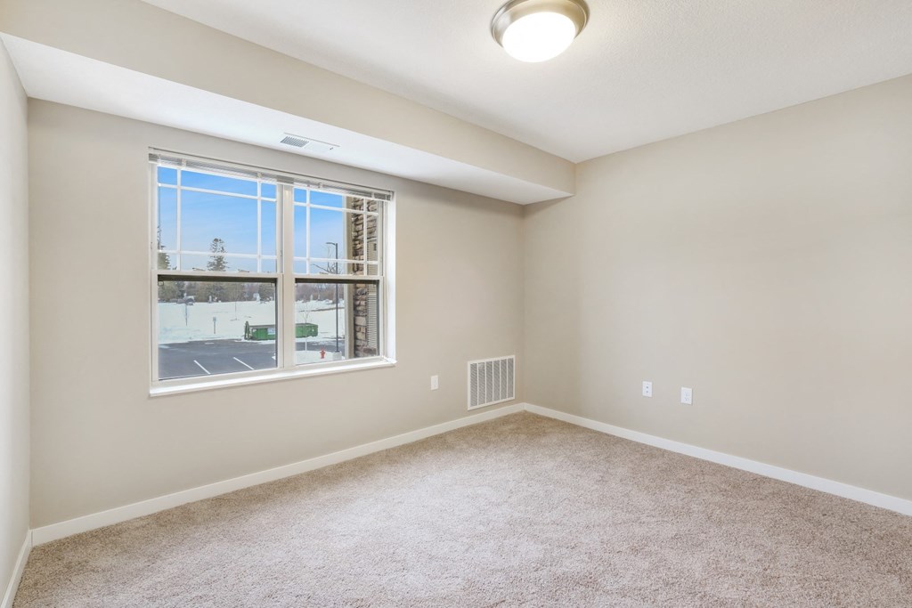 an empty living room with a large window and carpet