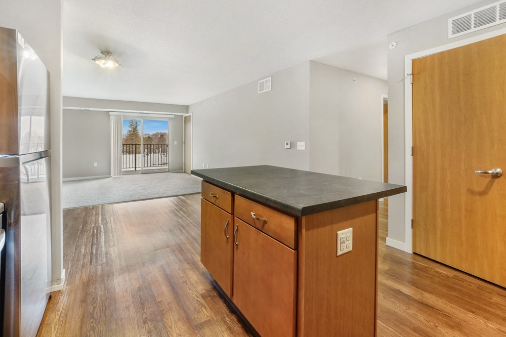 an empty kitchen with a counter top and a door to a living room