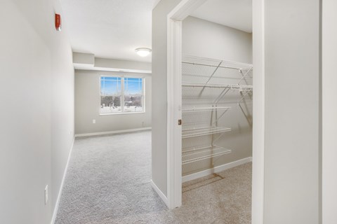 A white room with a window and a white closet.