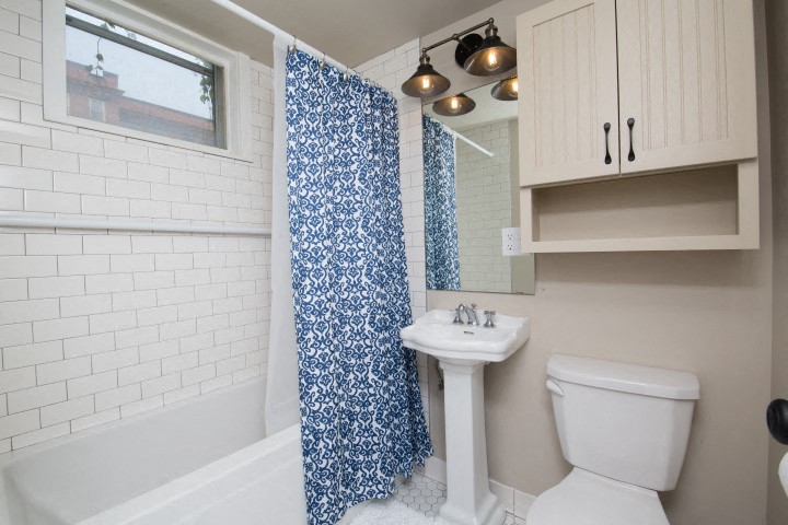 a bathroom with a white toilet and a blue shower curtain
