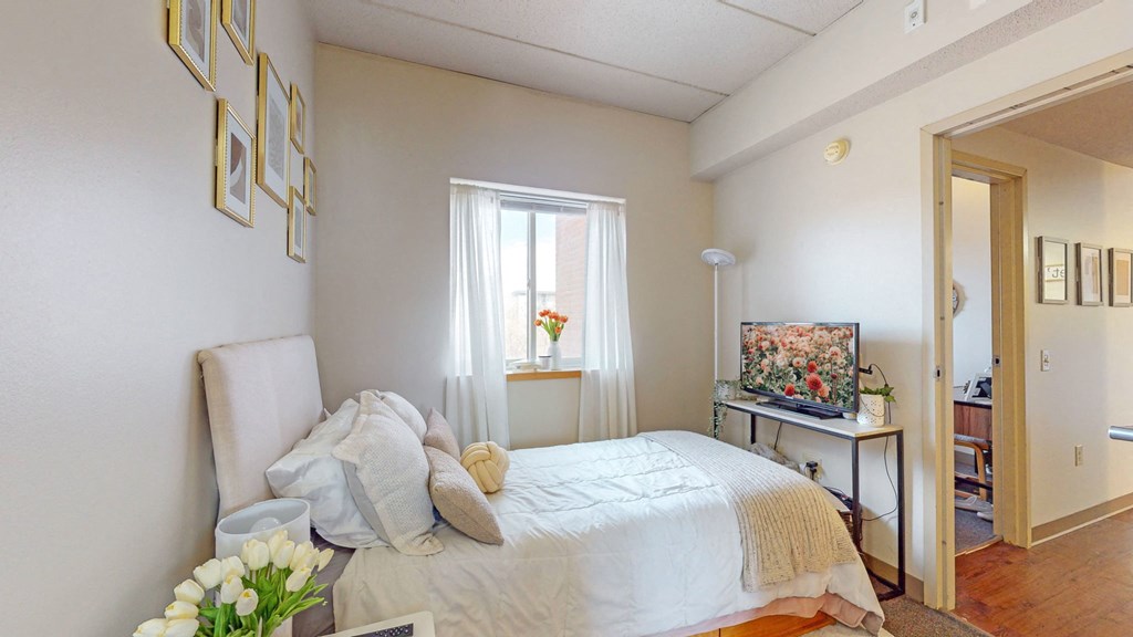 a bedroom with a bed and a desk and a window