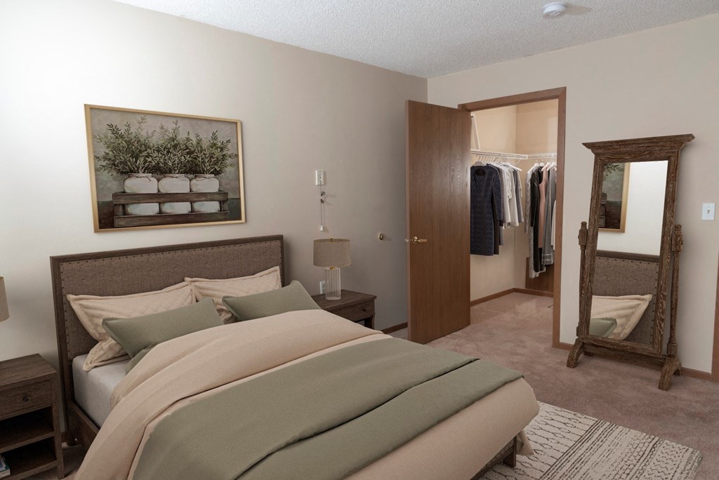 a bedroom with a bed and a mirror  at Briarcliff Apartments, a 55+ Community, Mahtomedi, MN