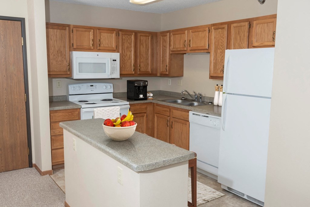 a kitchen with a white refrigerator freezer next to a white stove top oven  at Briarcliff Apartments, a 55+ Community, Mahtomedi, Minnesota