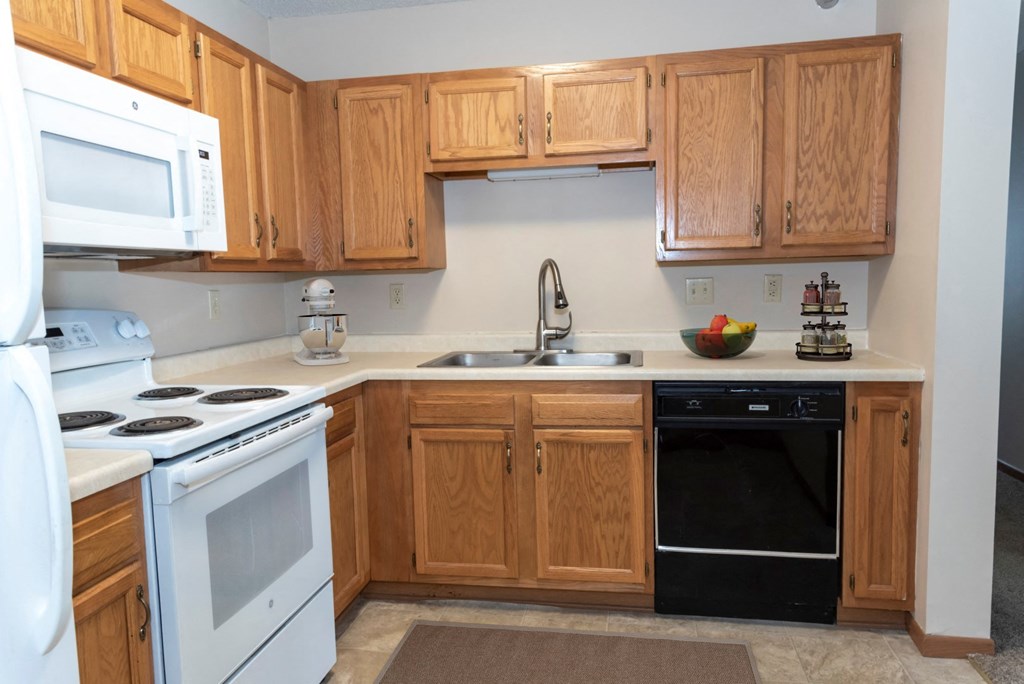 a kitchen with white appliances and wooden cabinets  at Briarcliff Apartments, a 55+ Community, Minnesota