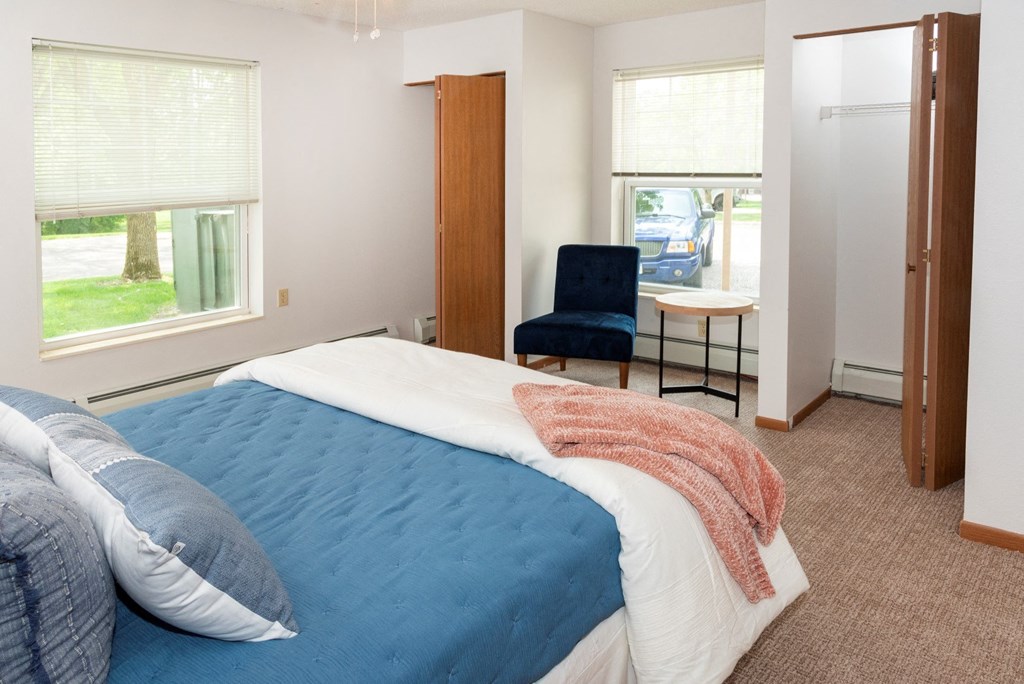 a bedroom with a bed and a chair in a room  at Briarcliff Apartments, a 55+ Community, Mahtomedi, MN, 55115