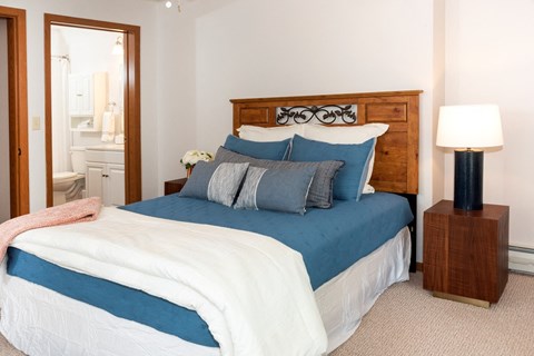 a bedroom with a bed and a nightstand  at Briarcliff Apartments, a 55+ Community, Mahtomedi, Minnesota