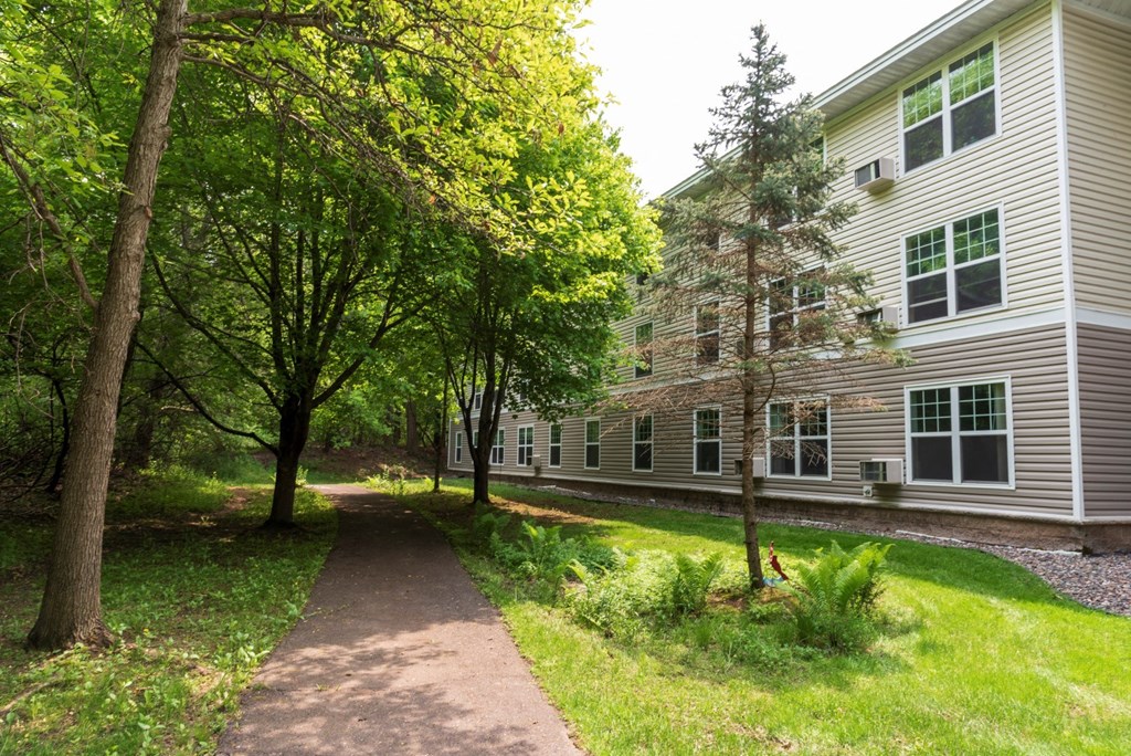 a path leading up to a building with trees on both sides of the path  at Briarcliff Apartments, a 55+ Community, Minnesota, 55115