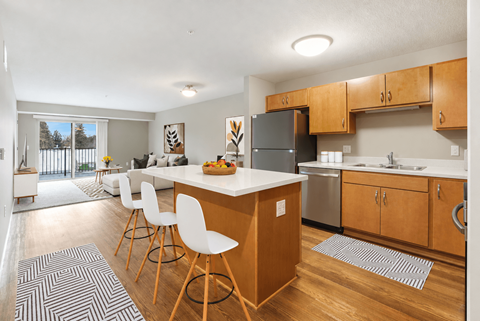 A kitchen with a white countertop and wooden bar stools.