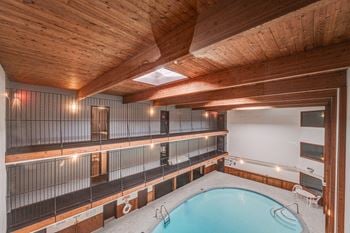 a pool in a room with wooden ceilings and white walls