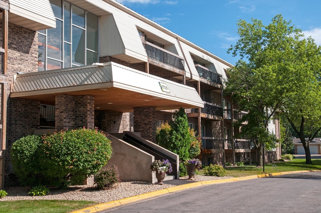 an apartment building with a road and trees in front of it