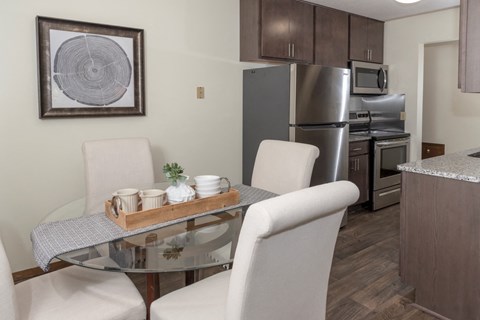 a dining room with a table and chairs and a kitchen with stainless steel appliances