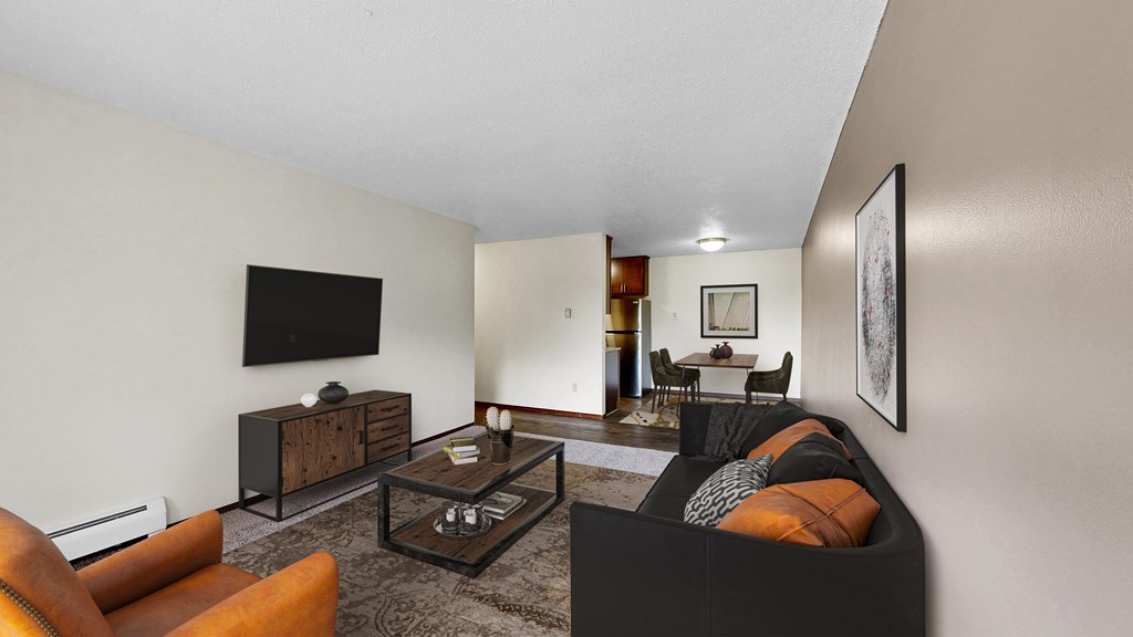 A living room with a black couch and a television on the wall.