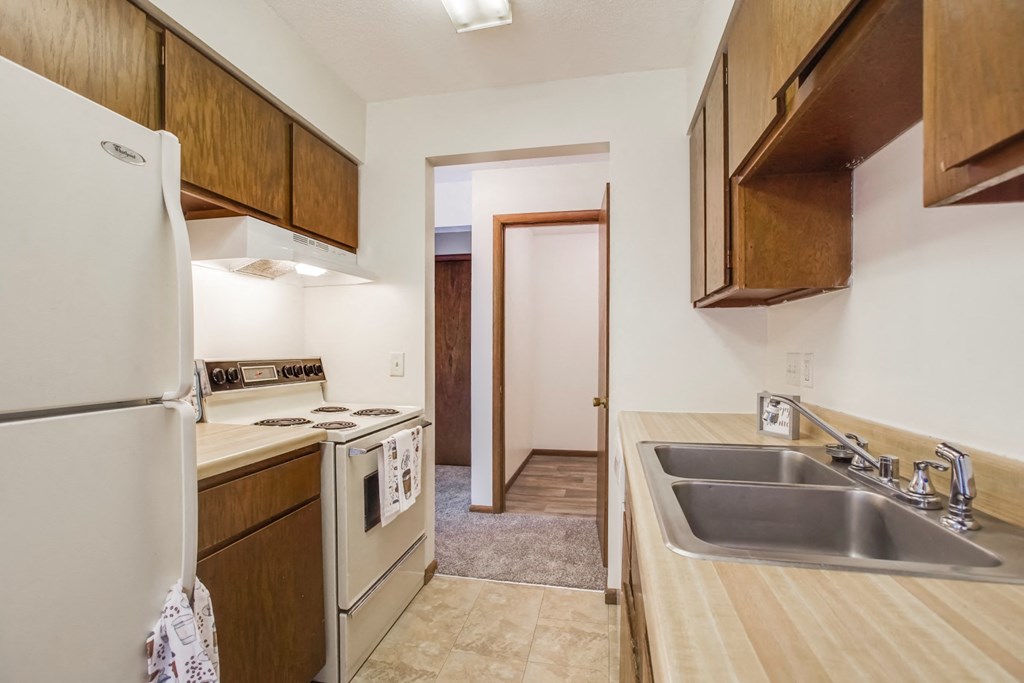 a kitchen with a sink stove and refrigerator and a door to a hallway