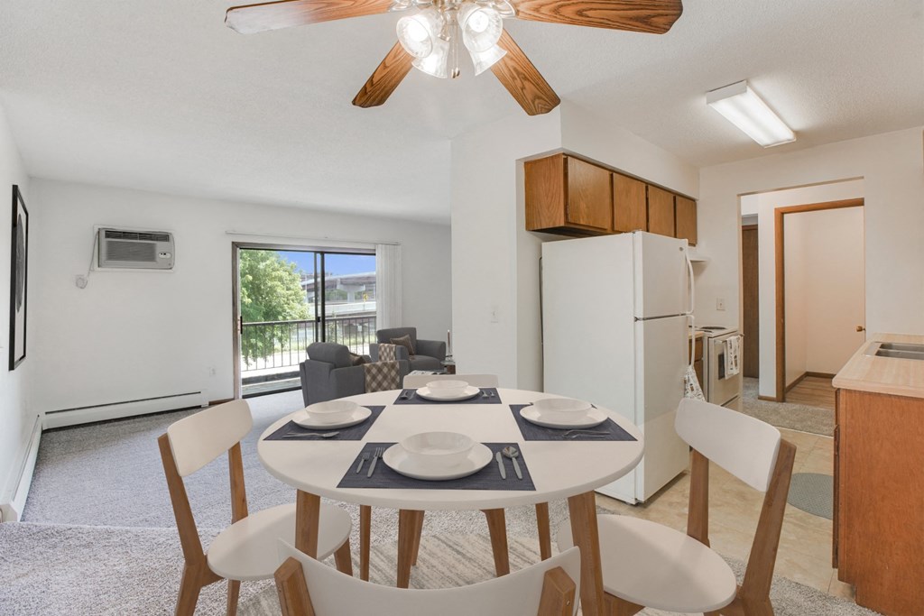 a dining room with a table and chairs and a kitchen with a refrigerator