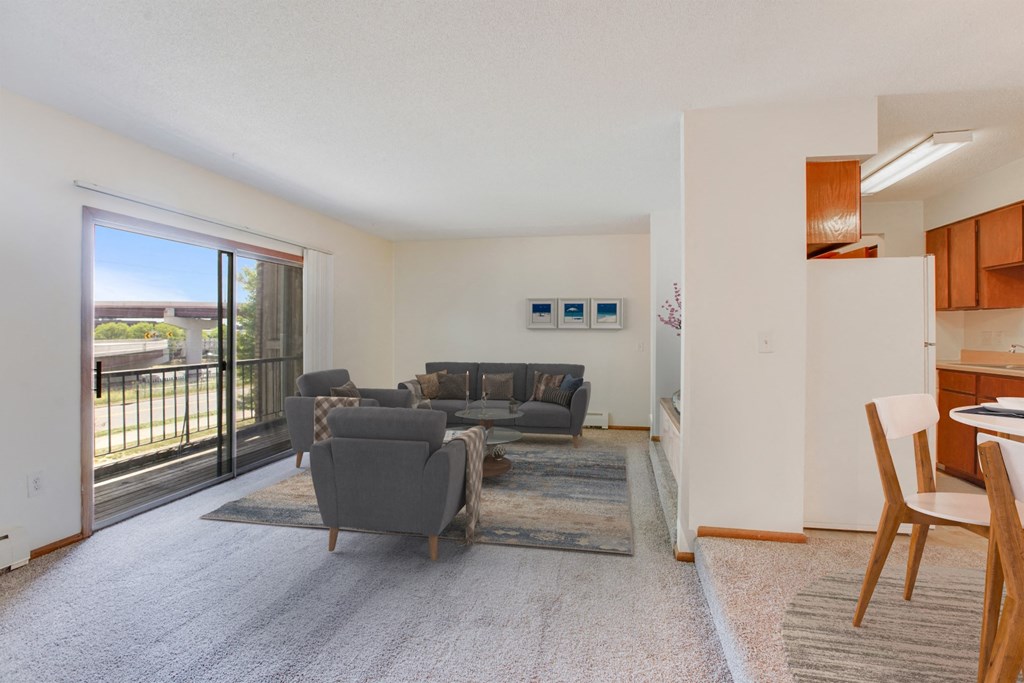 a living room with couches and a kitchen with a sliding glass door