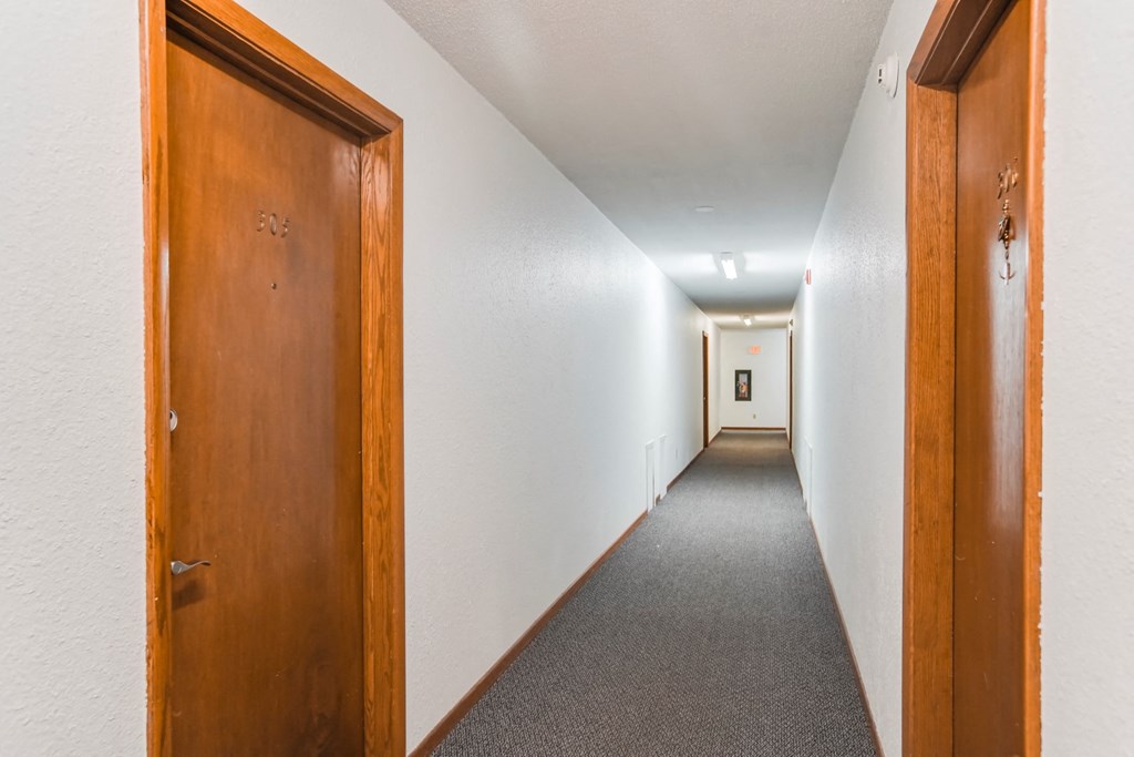 a hallway with wooden doors and a carpeted floor