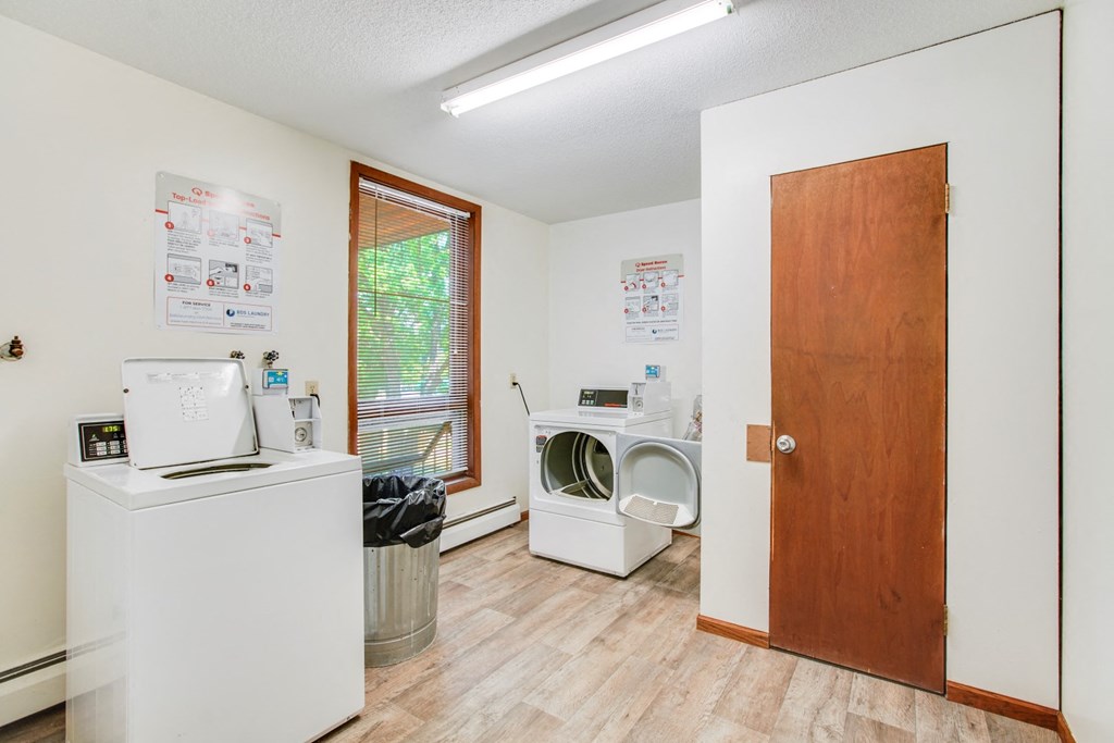 a laundry room with a washer and dryer and a door to a bathroom