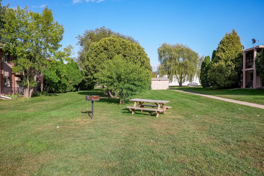 a picnic table in a park next to a fire pit