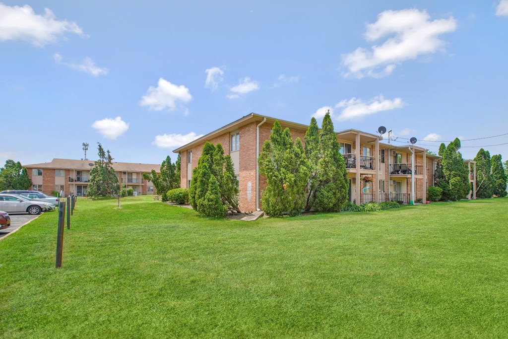 an apartment building with green grass and trees in front of it