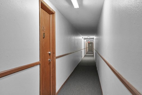a long hallway with wooden doors and white walls