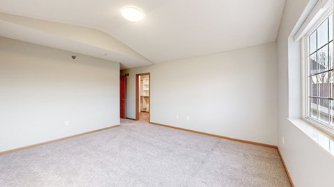 A room with a carpeted floor and a window on the right side.