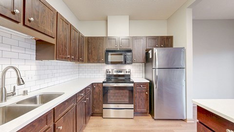 A kitchen with a stainless steel refrigerator, microwave, and oven.