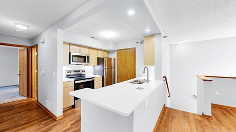 A kitchen with a white counter top and wooden floors.