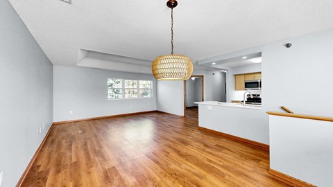 A room with wooden floors and a white ceiling with a hanging light fixture.