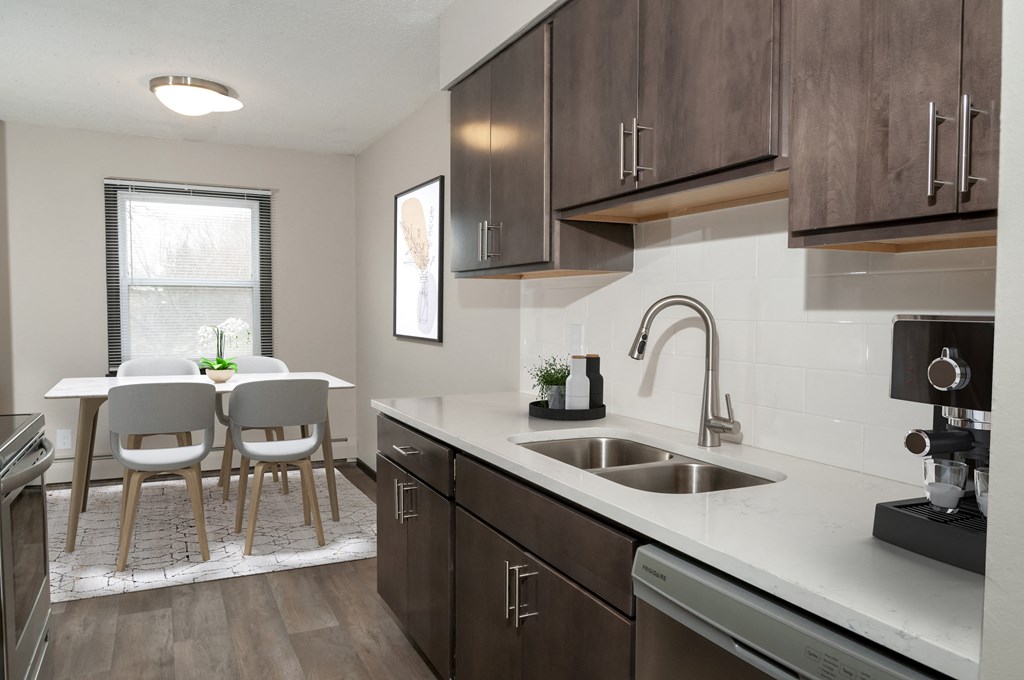 an apartment kitchen with a sink and a table with chairs