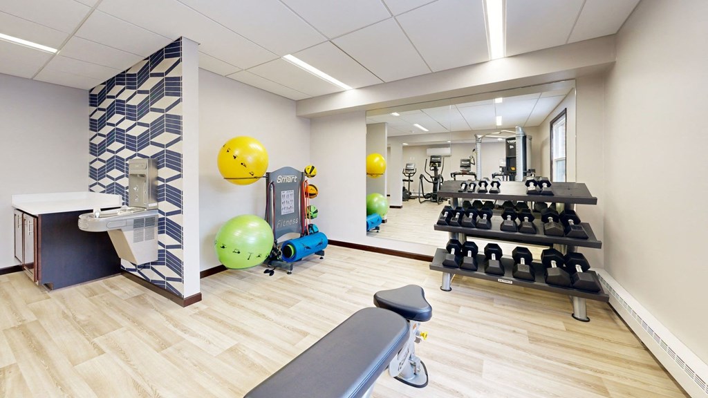 a gym with weights and a yellow ball on the wall