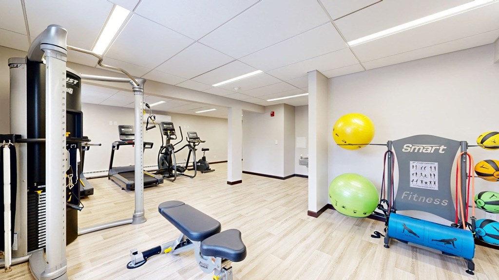 a gym with exercise equipment and a yellow ball on the wall