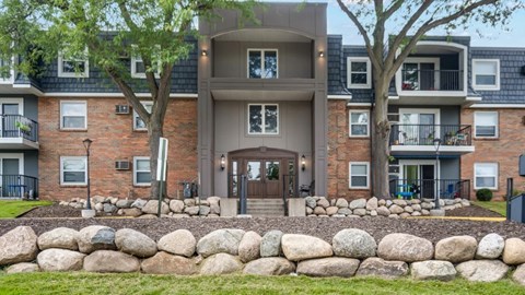 A modern apartment building with a stone wall in front.