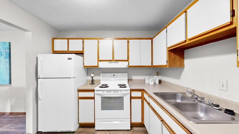 A white refrigerator and oven in a kitchen with wooden cabinets.