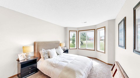 A bedroom with a large bed and a nightstand with a lamp.