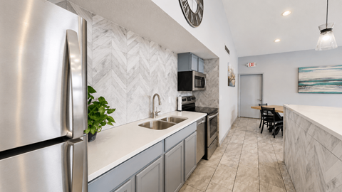 A modern kitchen with a stainless steel refrigerator and a marble backsplash.