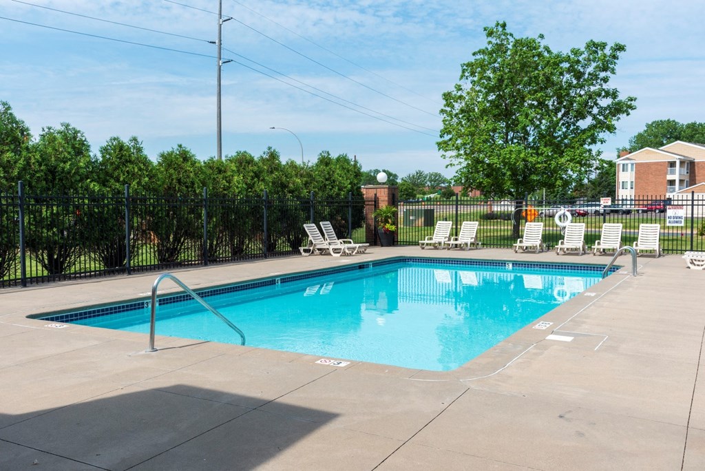 a swimming pool with chaise lounge chairs and trees in the background