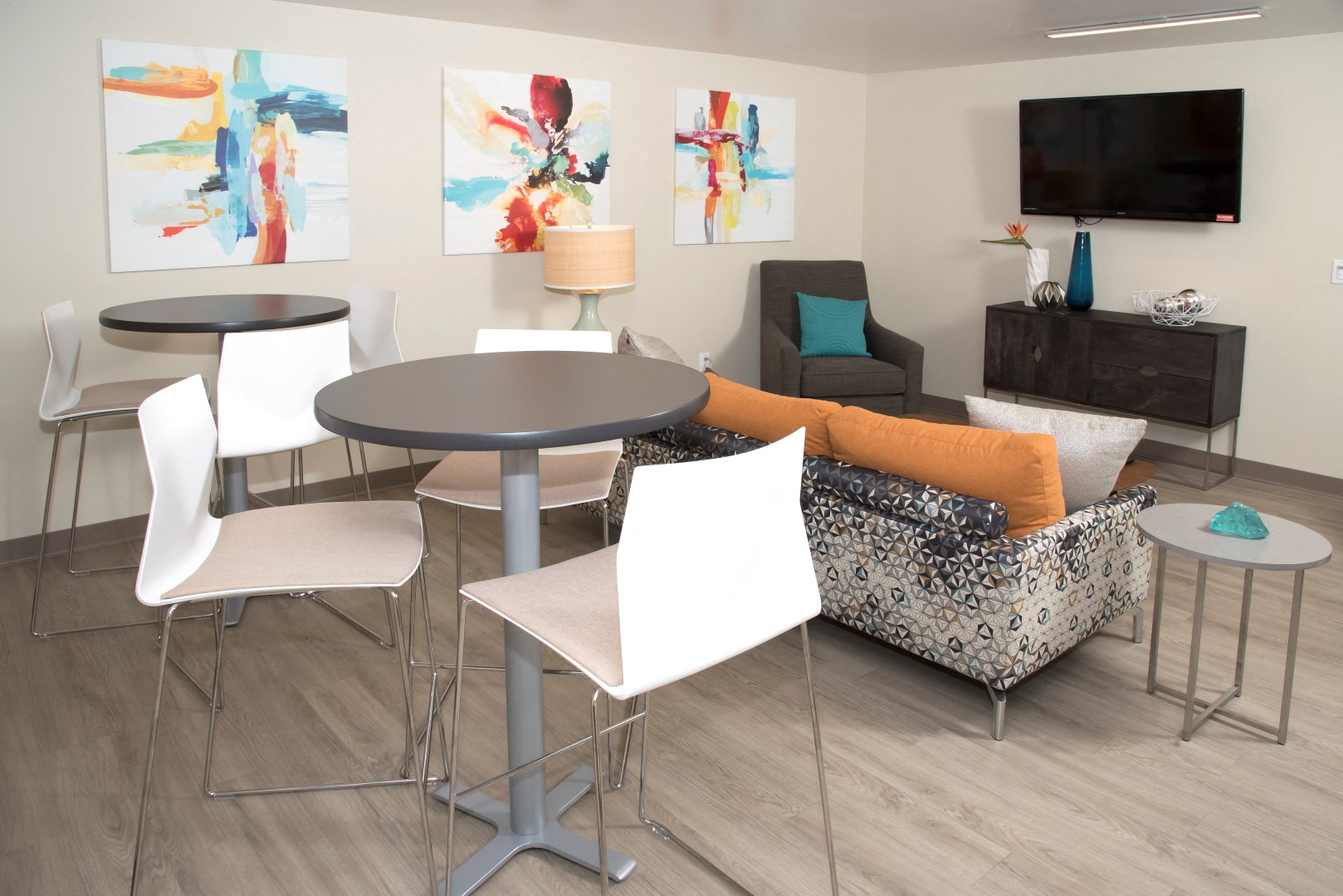 A laundry lounge with a grey table surrounded by white chairs.