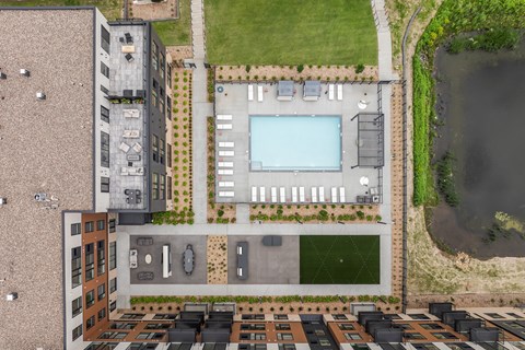 A bird's eye view of a building with a pool and parking lot.