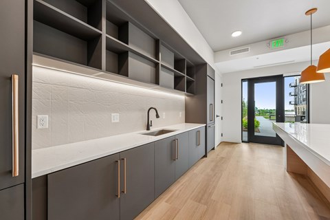 A modern kitchen with dark grey cabinets and a wooden floor.
